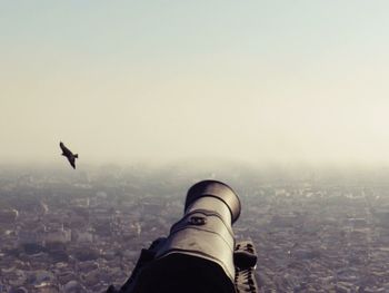 Close-up of airplane flying over cityscape against sky