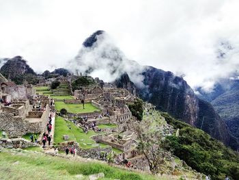 Panoramic view of people on mountain against cloudy sky