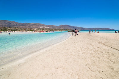 People on beach against blue sky