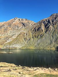 Scenic view of lake and mountains against clear blue sky