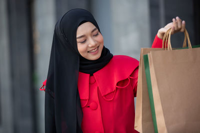 Mid adult woman standing against red wall