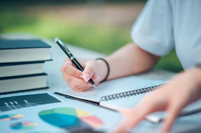 Midsection of woman reading book on table