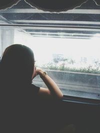 Rear view of man looking through window