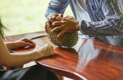 Midsection of woman holding ice cream on table