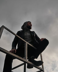 Low angle view of man sitting against sky