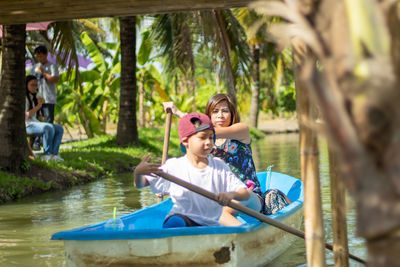 Mother and son rowing boat in water