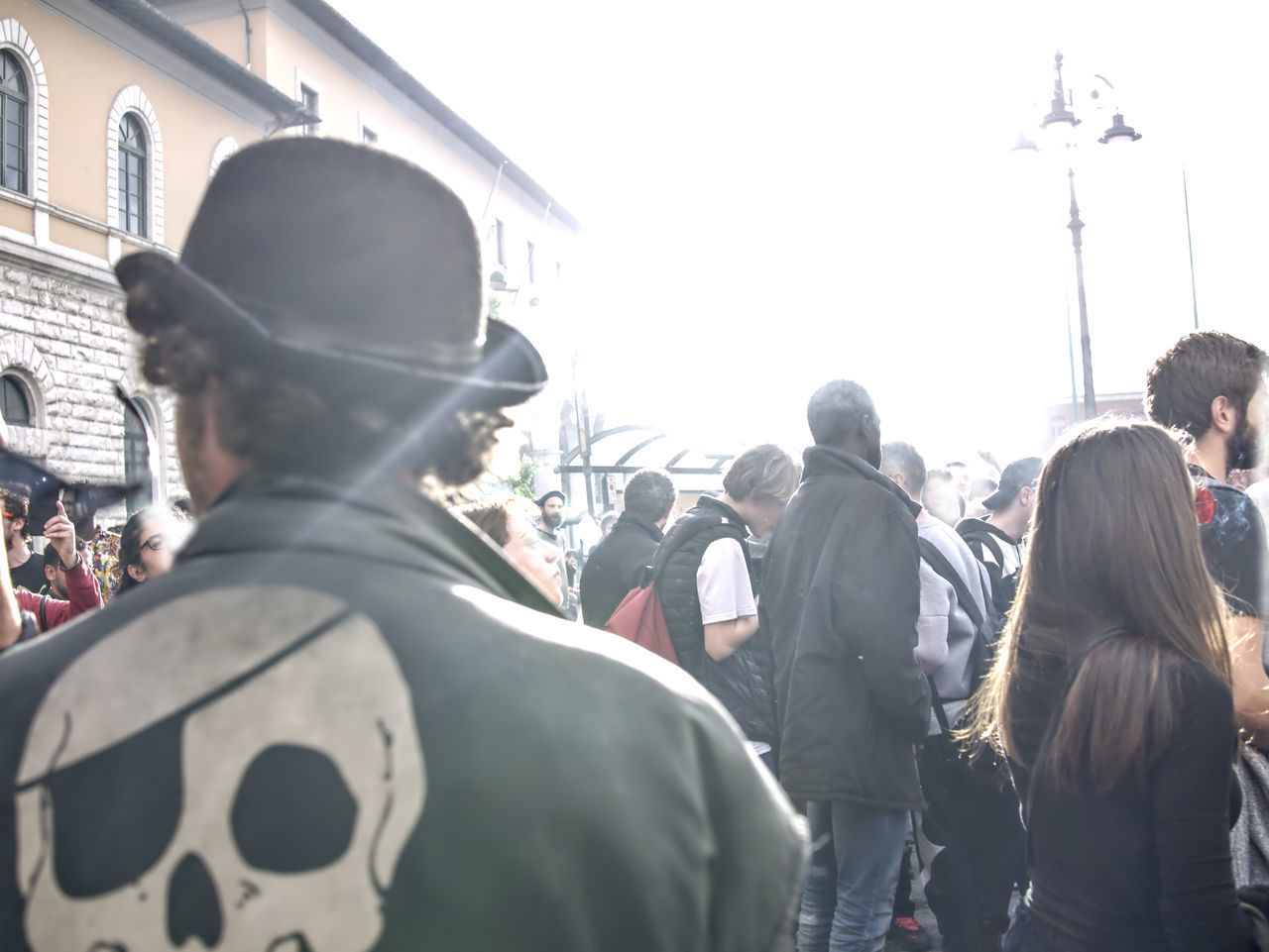 REAR VIEW OF PEOPLE STANDING ON CITY STREET