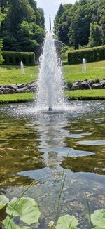 Water splashing in fountain against lake