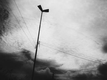 Low angle view of power lines against cloudy sky