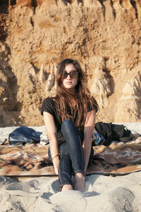 Portrait of woman sitting on sand at beach