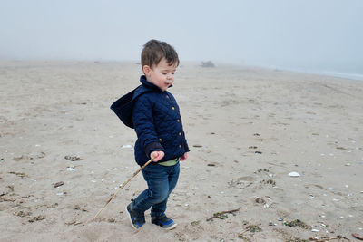 Young boy playing with his stick on the beach