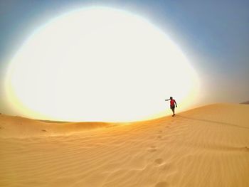 Mid distance of man walking on sand dune at desert