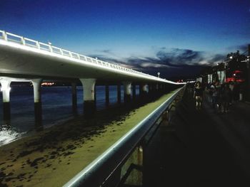 Illuminated bridge over sea against sky in city