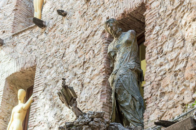 Low angle view of old statue against wall