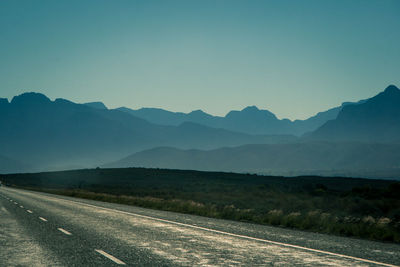 Road by mountains against sky