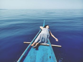 High angle view of woman lying on boat in sea against sky