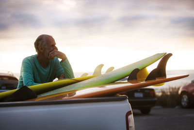 Senior man with surfboards by car