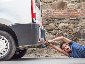 Portrait of shocked young man pulled by car on street