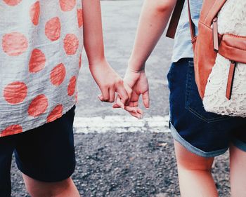 Midsection of girls holding hands on street