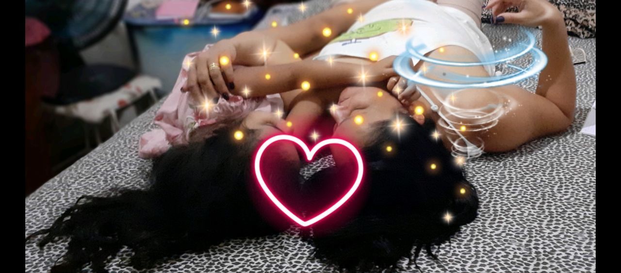 MIDSECTION OF WOMAN MAKING HEART SHAPE ON ILLUMINATED