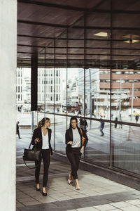 Businesswomen talking while walking on footpath