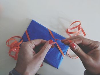 Cropped hands of woman tying ribbon on gift