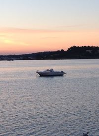 Boat sailing in sea at sunset