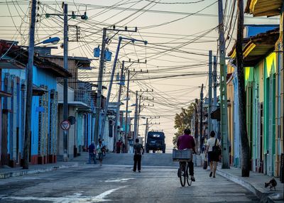 Telephone poles by street in city against sky