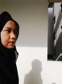 Close-up of young woman standing against wall