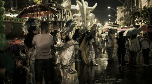 Rear view of people walking on wet street during rainy season