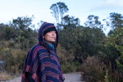 Portrait of colombian native american man in traditional clothing against forest