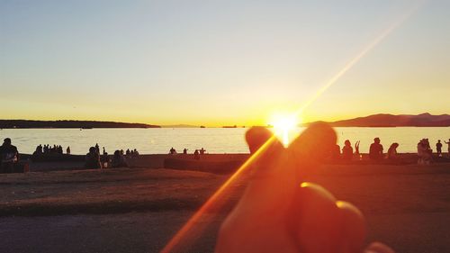 People on beach against sky during sunset