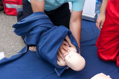 Midsection of instructor teaching paramedic while performing cpr on dummy