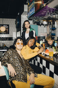 Portrait of male and female friends at bar counter in restaurant