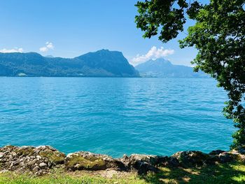 Scenic view of sea and mountains against blue sky