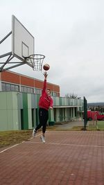 Man playing basketball hoop against sky