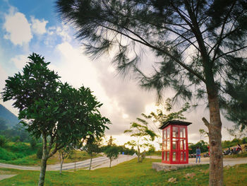 Trees and house on field against sky