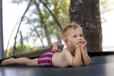 Portrait of boy looking away while sitting on tree