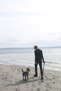 Rear view of man walking with dog on beach