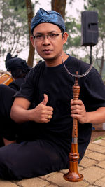 Portrait of young man sitting outdoors holding a traditional flute