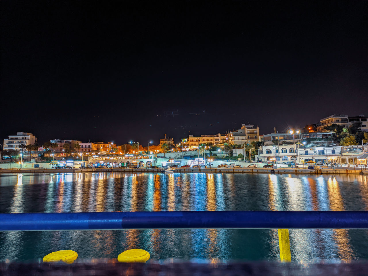 ILLUMINATED BUILDINGS BY RIVER AGAINST SKY