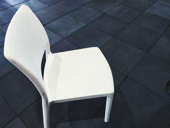 High angle view of empty white chair on tiled floor