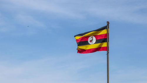 Low angle view of uganda flag against blue sky