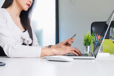 Woman using mobile phone while sitting on table