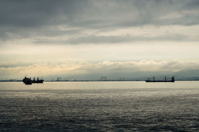 Boat sailing in sea against cloudy sky