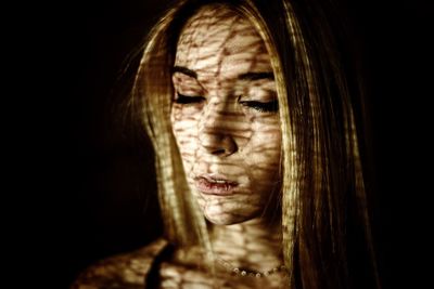 Woman with shadow on face against black background