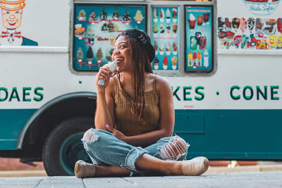 Young woman looking away while sitting against graffiti