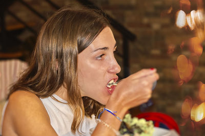 Side view of young woman drinking glass