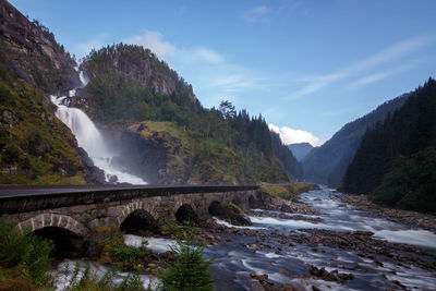 View of arch bridge and waterfall against sky