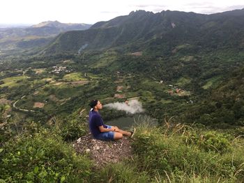 Side view of man sitting on mountain